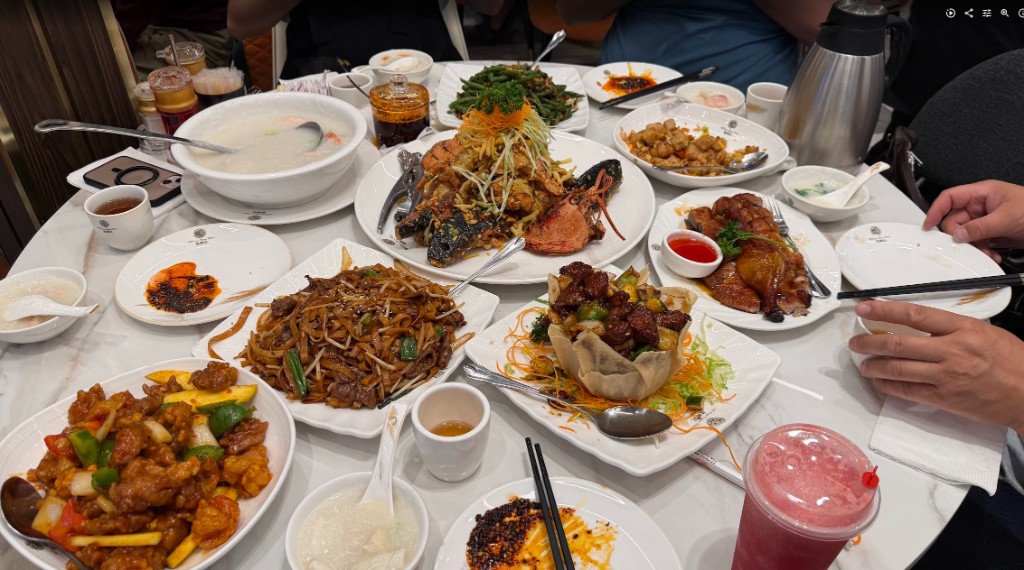 A large spread of Chinese dishes at Mr Congee including lobster, duck, noodles, black pepper beef, and congee
