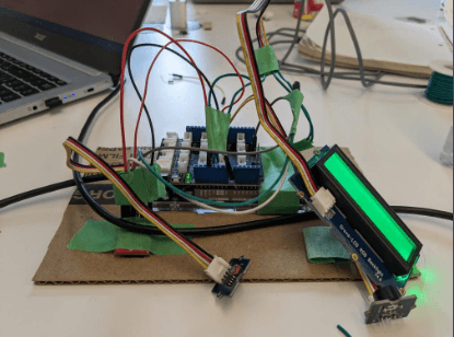 Inside the soap alarm: an Arduino with a breadboard, wiring, and a green LCD module taped onto a cardboard base