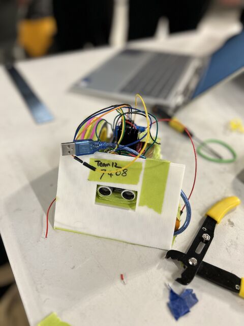 Close-up of the sumo robot with an ultrasonic sensor on the front and an Arduino with wiring stacked on top