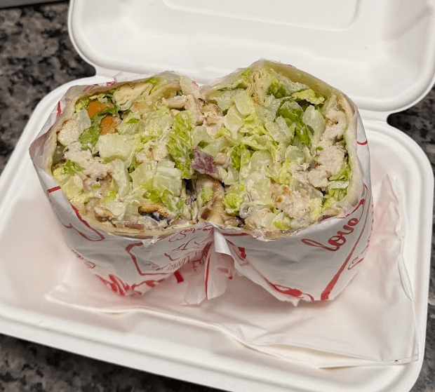 Chicken caesar wrap from Grandma Loves You in a takeout container, cut in half