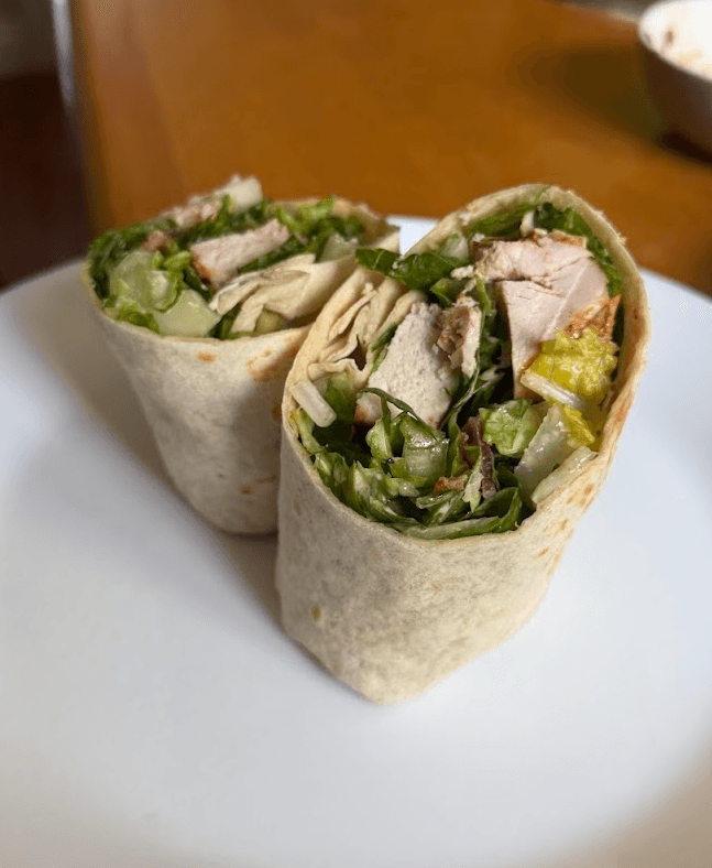 My homemade chicken caesar wrap cut in half on a white plate